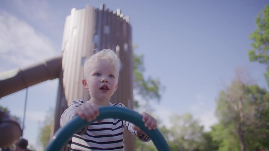 A child riding a playground spring rider holding onto the handle