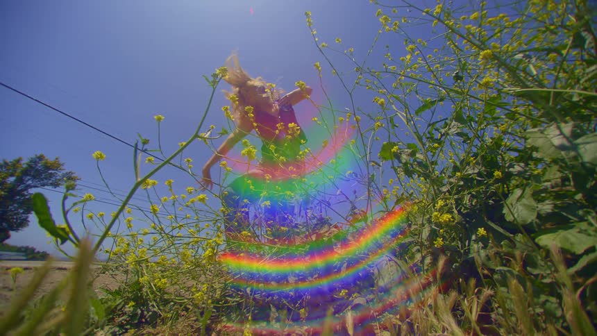 Bed of green flowers in the foreground and in the background a blonde woman dancing
