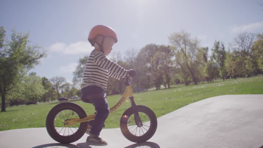 Blonde boy riding a bicycle on a relief in a park