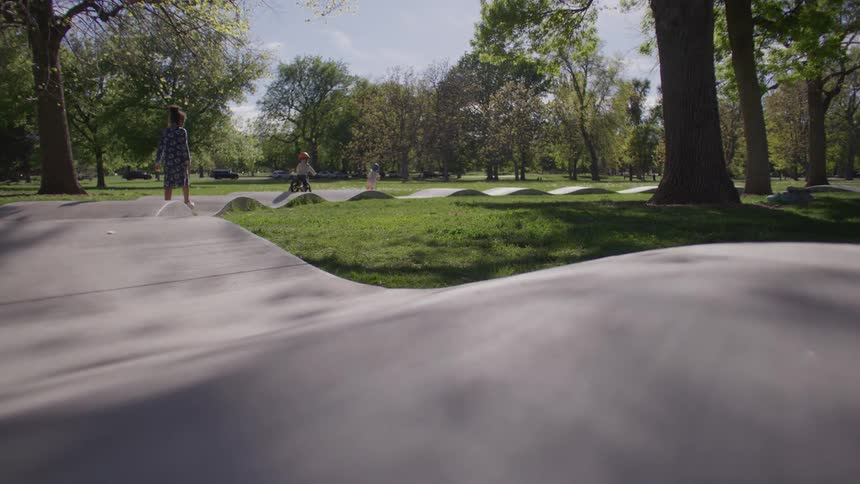 Small children in a park riding bicycles on a relief