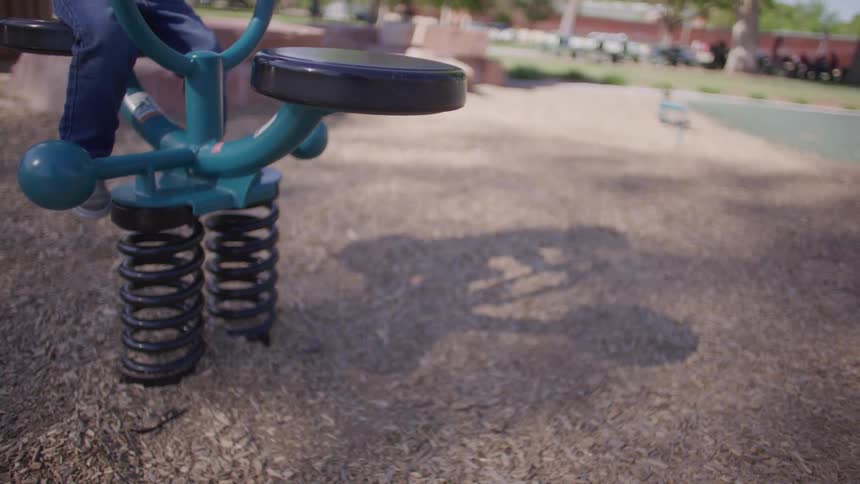 Legs of a small child playing on a spring toy in a park