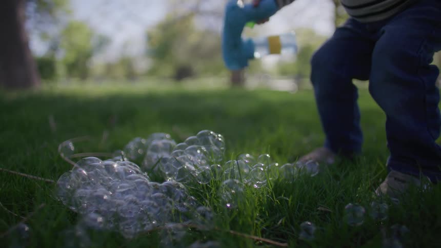 Legs of a child jumping on the grass on top of soap bubbles