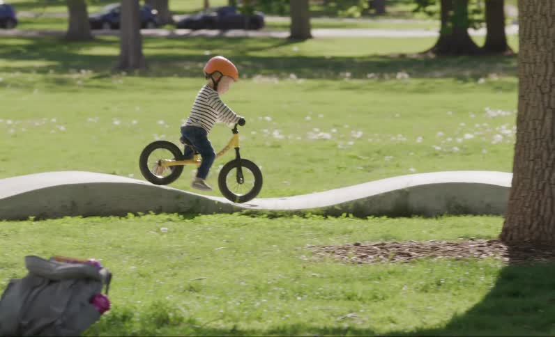 Little boy stands in a helmet riding a bicycle in a relief park