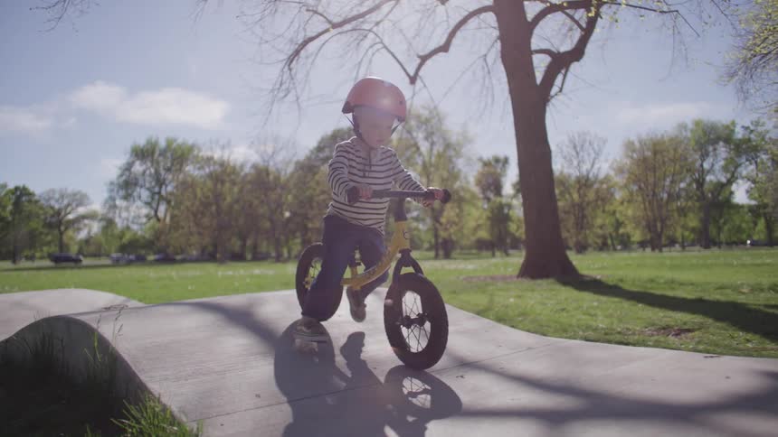 Blonde boy in a helmet riding a bicycle without training wheels in a park