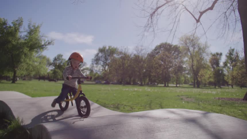A child wearing a helmet and riding a bicycle on a path in a park