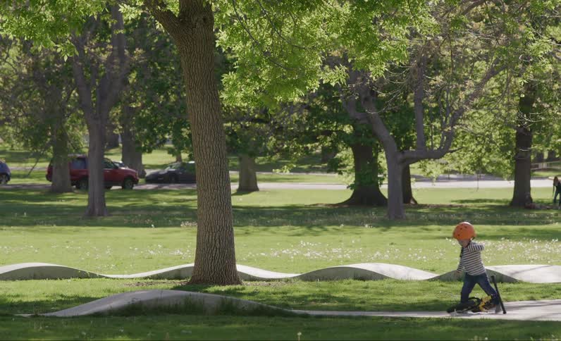 Little boy dropping his bike and running through the grass in the park