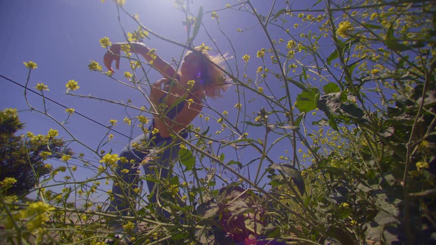 Woman dancing in a field with green plants