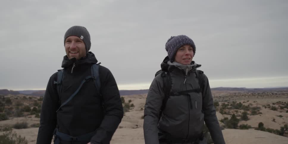 Bundled up couple walking in a flat wilderness on a very cloudy cold day