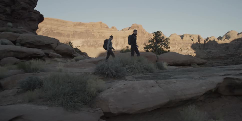 Man and woman hiking through rocky wilderness on a clear day