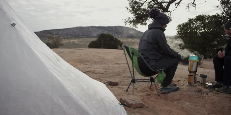 Two people are sitting at their camp cooking