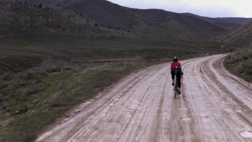 A person rides a bicycle on a muddy road