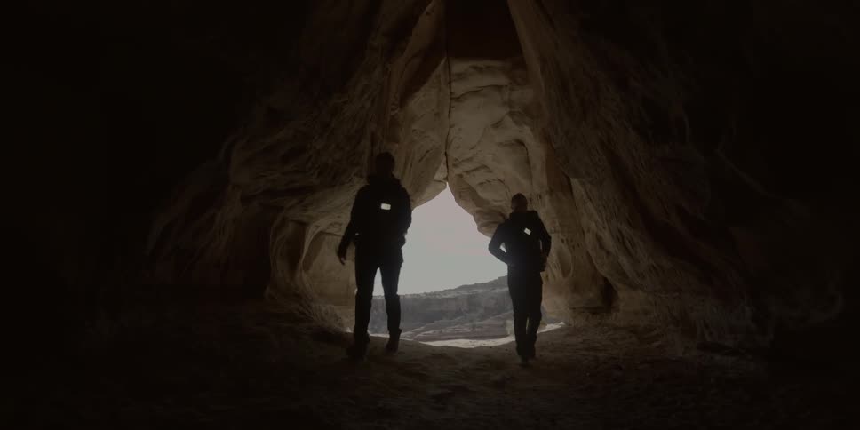 Two people walking into a cave