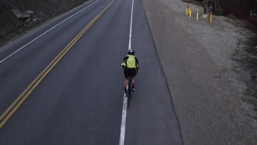 Cyclist riding his bike on the berm of a paved road