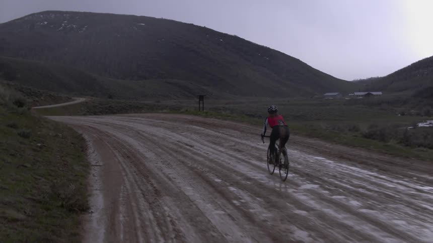 A person riding a bike down a muddy road in the country