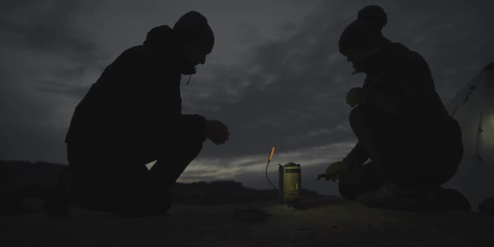 A man and woman sit around a small fire