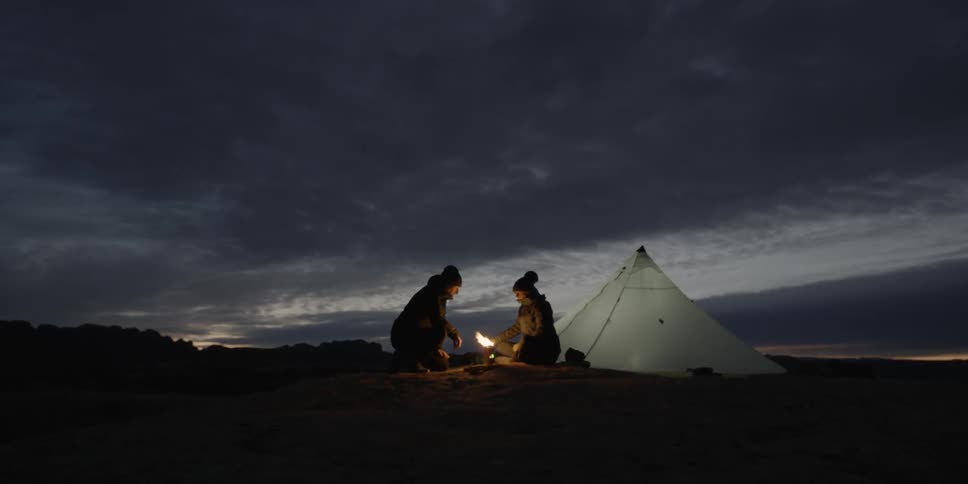 Time-lapse of a couple sitting outside their tent at sunset