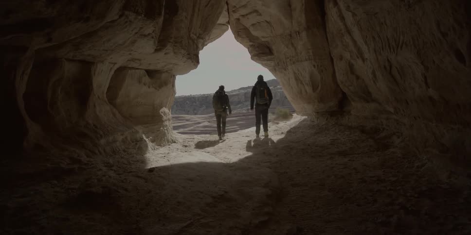 Hikers walk through a rock crevice and sit on the edge