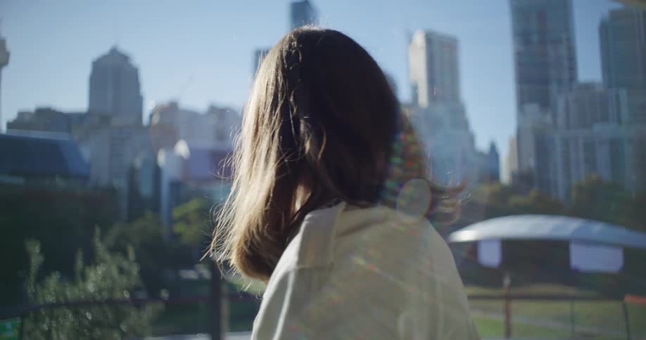 A woman is looking back and then turns and looks at buildings in a metropolitan city