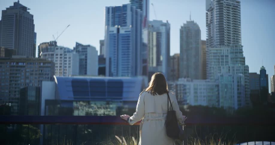 Woman in a white coat observing buildings in a metropolis