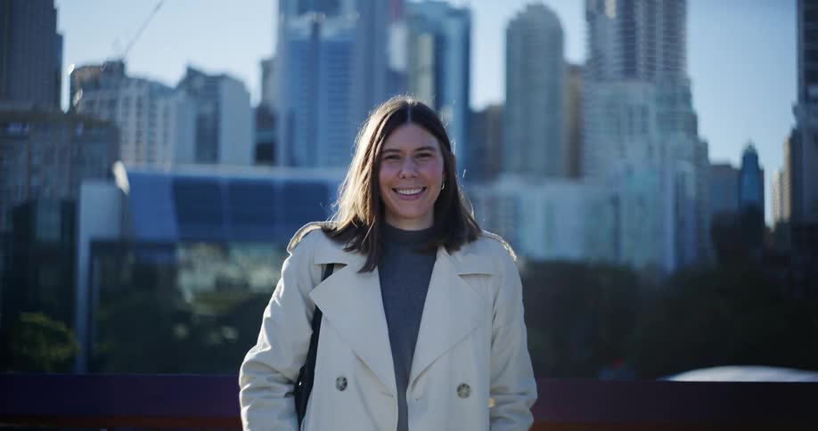Woman smiles while standing outdoors with the city skyline in the background