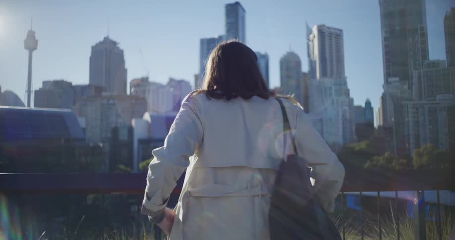 A woman wearing a coat steps outdoors to look at the city skyline