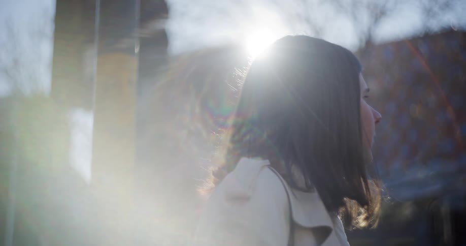 A woman wearing a coat looks around at city buildings