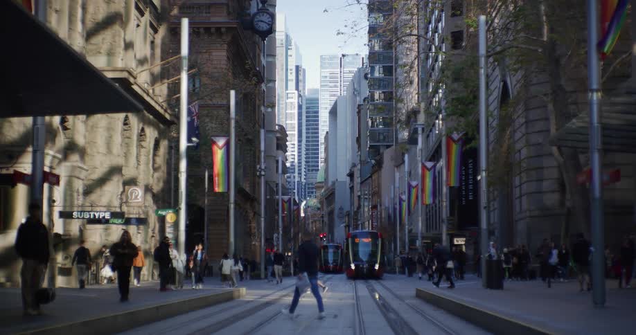 Pedestrians cross through downtown intersection as public transportation approaches