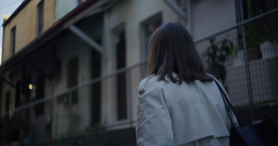 Woman wearing a coat walks past fenced in row houses