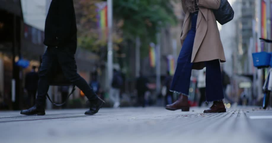 Various people walk across a city street in a downtown area