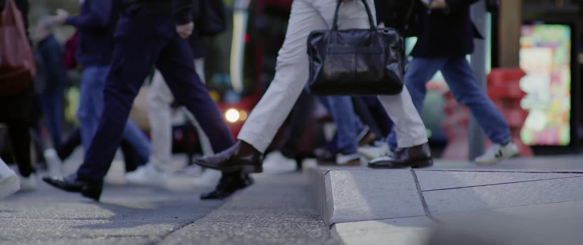 A group of people cross the street in a downtown metropolitan area