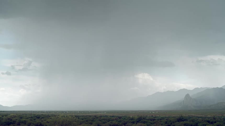 A lightning strike pierces through dark stormy skies illuminating the landscape below