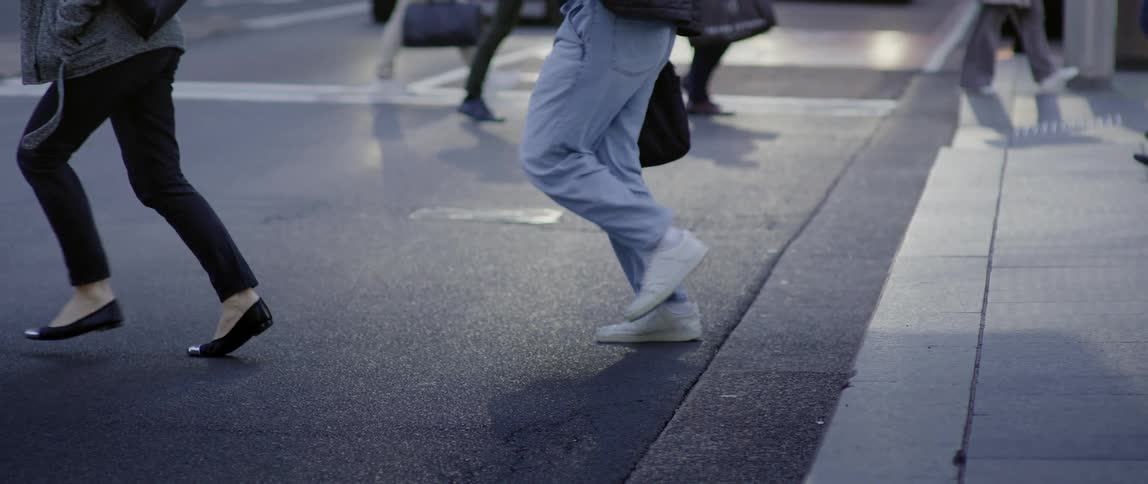 A number of people walk and run across a city street