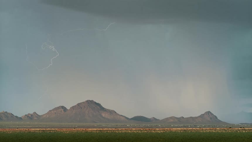 Active lightning storm hovering over the mountains in the middle of the afternoon