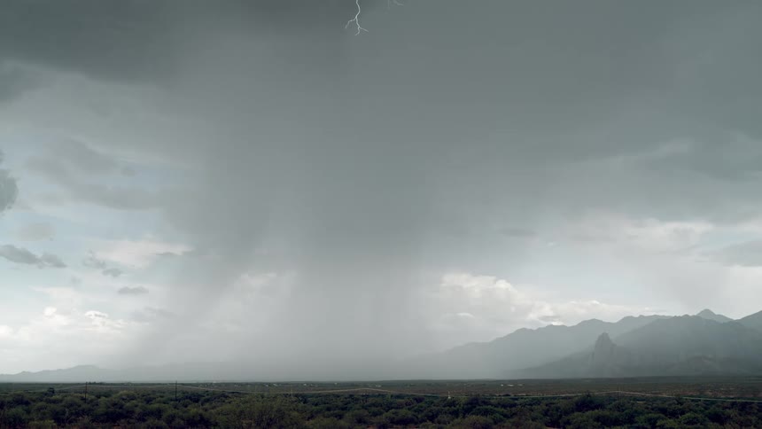 Some lightning from a storm from a black cloud falling to the ground in a rural region