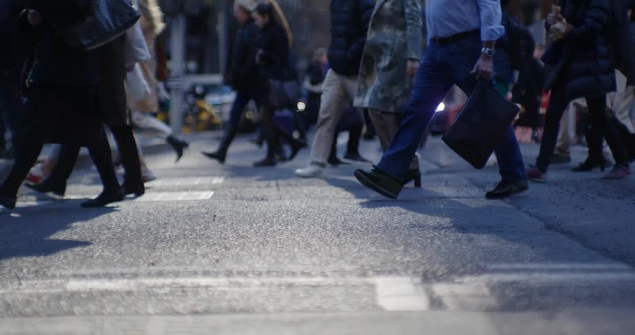 Pedestrians crossing the street in both directions in front of multiple vehicles