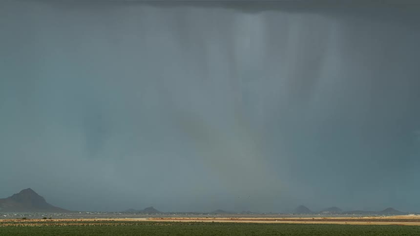 A lightning strike pierces through dark stormy skies illuminating the landscape below