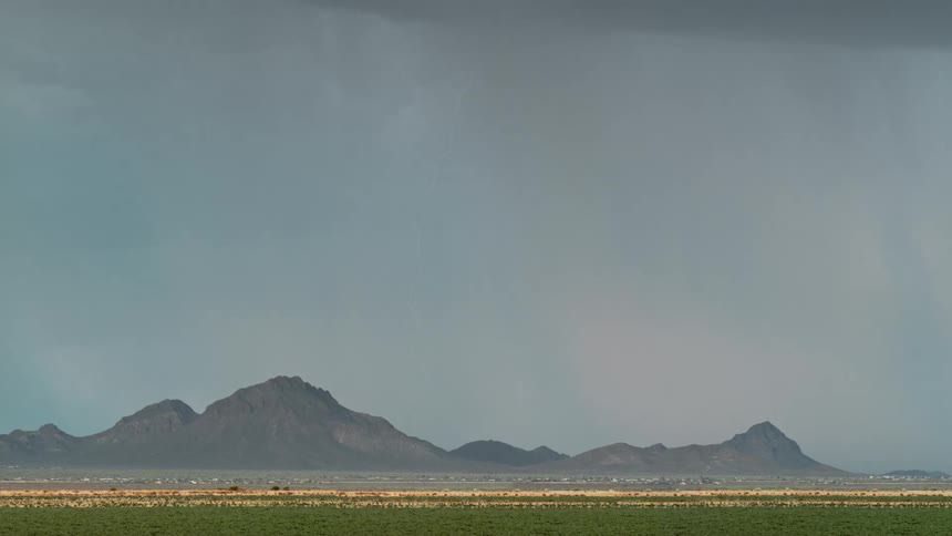 Lightning strikes the mountains bordering a rural town during a thunderstorm