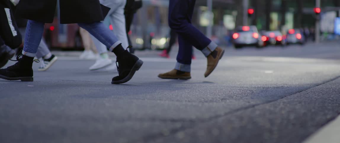 A crowd of men and women walk across a city street