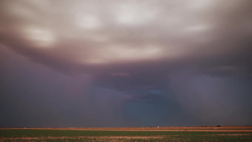 A large wall cloud and storms unleash lightening over a farm in a rural area