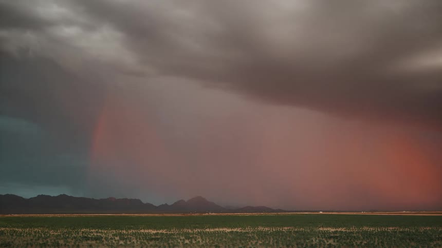 Red sky with clouds and lightning above a field and with the silhouette of mountains on the horizon