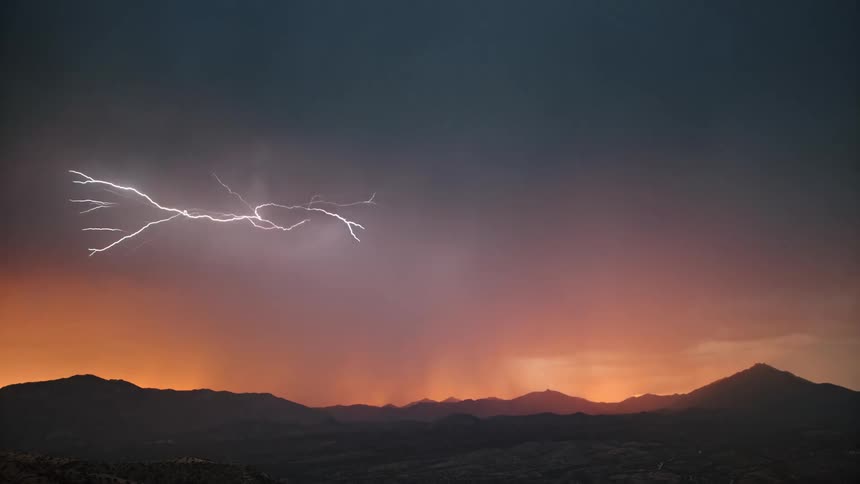 Storm with thunder in a reddish sky above mountains