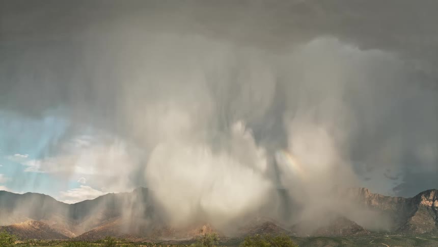 A huge white cloud in front of a mountain range and bright lightning falling next to it
