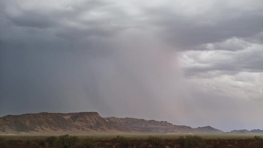 Lightning strikes above a mountain range and a grassland under dark cloudy skies