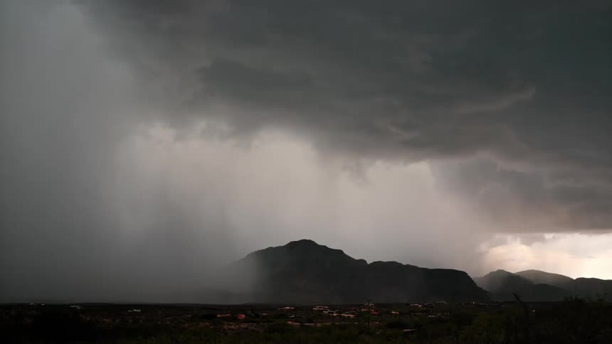 A dramatic landscape with dark clouds and a bright lightning bolt striking down towards a mountain range