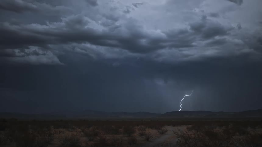 Storm with lightning above mountains in a field