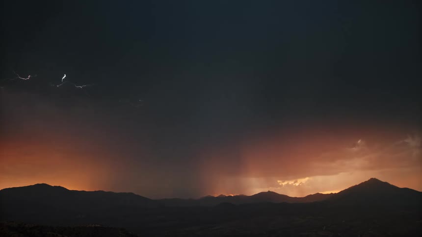 Silhouette of mountains on a day with storm and thunder in a reddish sky