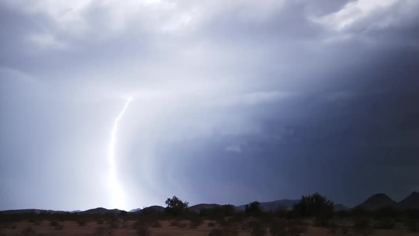 Several bright rays falling in a region at night and gray clouds dominate the sky