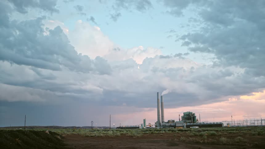 Lightning strikes on the plains near a power plant at sunset