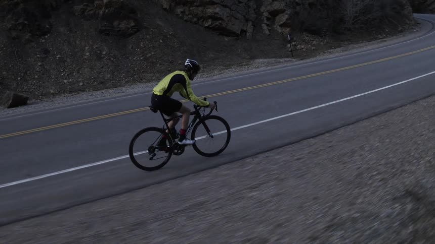 A person stands on the pedals to bike up a steep road