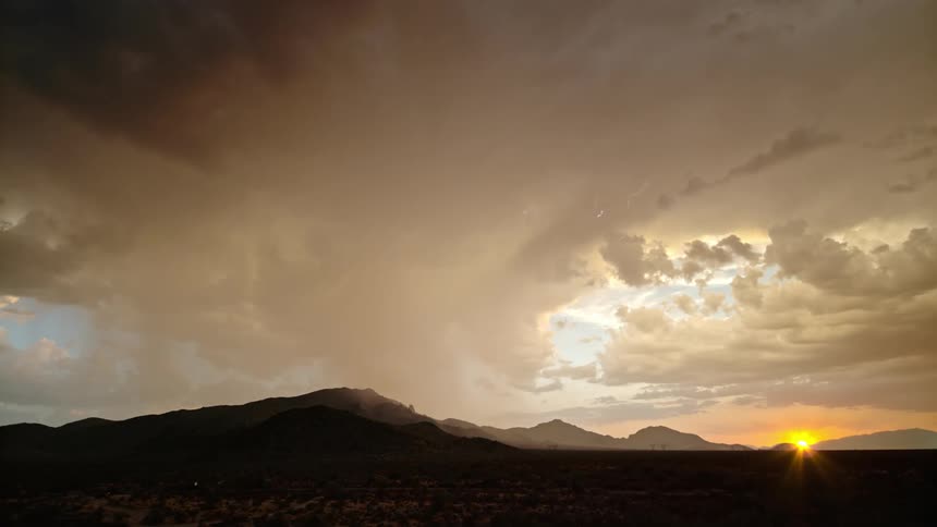 A storm rages above the mountains at sunrise